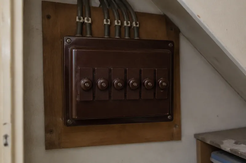 Consumer unit replacement in Bridgwater: illustration of an old brown fuse box with rewireable fuses under a staircase